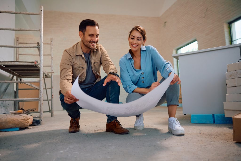 Happy couple going through housing plans at their renovating home. Copy space.