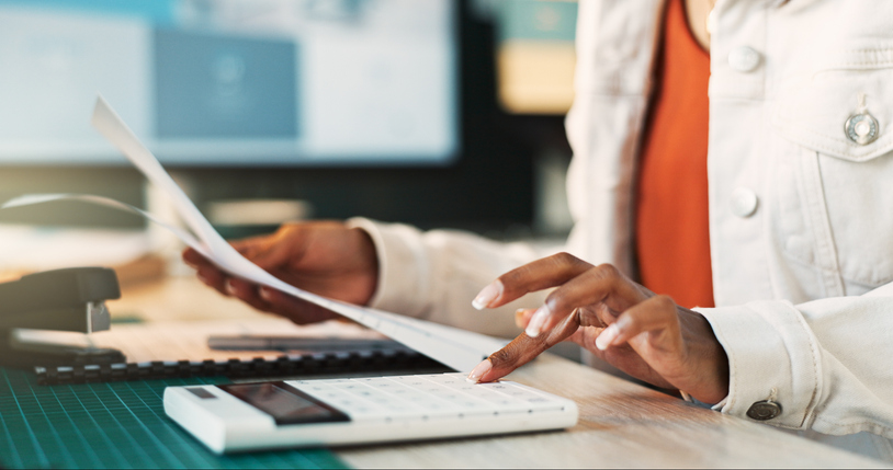 Calculator, hands and paperwork on desk, office and closeup of accountant, numbers and finance of business. Bookkeeping, table and person with documents, profit and tax of company, revenue and invest